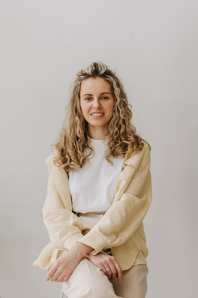 a person with long hair wearing a white shirt and a cream cardigan